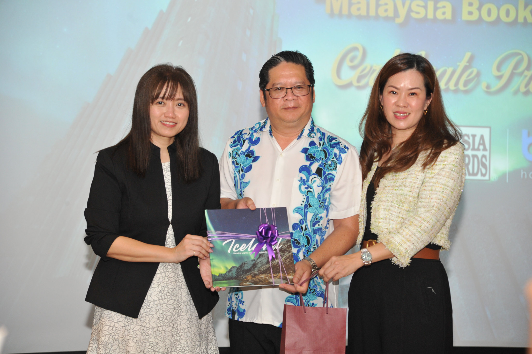 张文绮(右)颁发纪念品给予生意伙伴郑志富及其太太，感谢他们多年对BP Holiday的支持和付出。