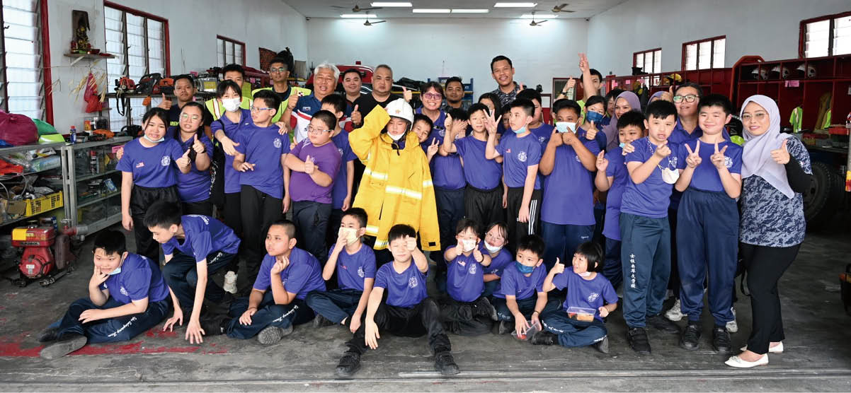 余深恩(后排左4)率领29名特殊儿童到访甲洞自愿消防拯救局,后排左6为邓伟铭。